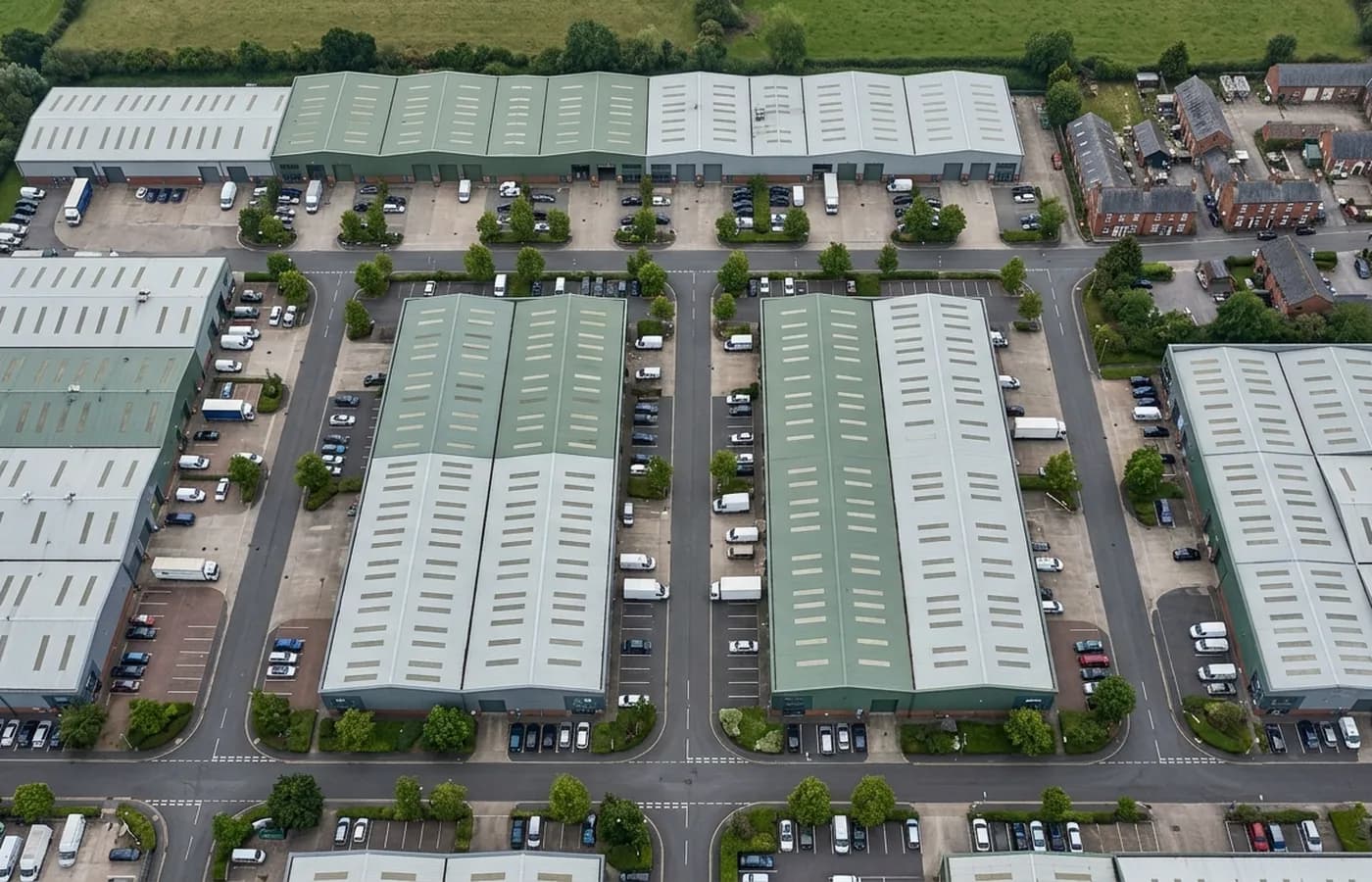 A Devon trade estate photographed from directly above, a grid of industrial roofs with rooflight strips and box gutters