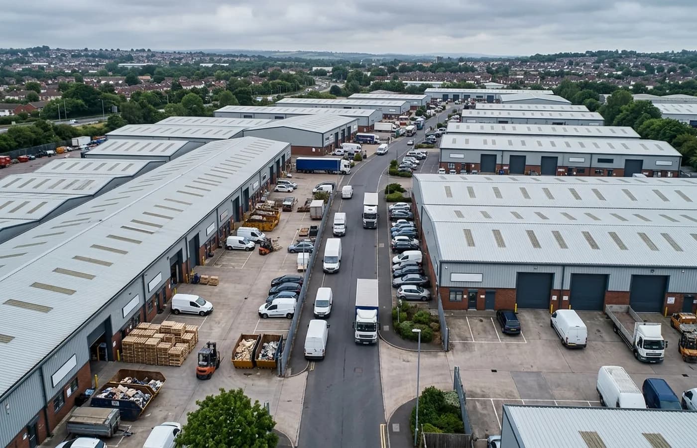A trade estate on the edge of a Devon city, rows of portal frame units with shallow pitch metal roofs, roller shutters and yards